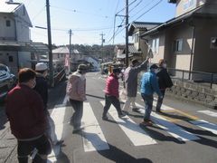 交通安全、横断歩道を渡ります。利用者さんの手にはゴミ袋。散歩の際はゴミ拾いも欠かしません。